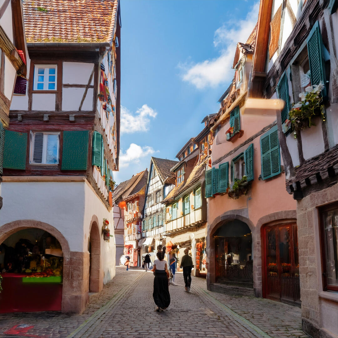 Favoriser les liens locaux et les valeurs de proximité grâce à KUTI Scène de marché local en Alsace avec des maisons traditionnelles et des habitants souriants